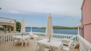 Una terraza con mesas y sillas blancas, vista al mar y un arco de piedra.