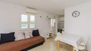 Una habitación con sofá, mesa de comedor y un reloj en la pared.