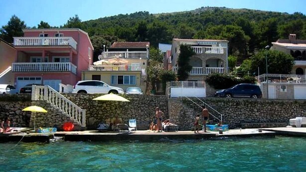 Una piscina con una pared de piedra, una escalera y algunas personas.