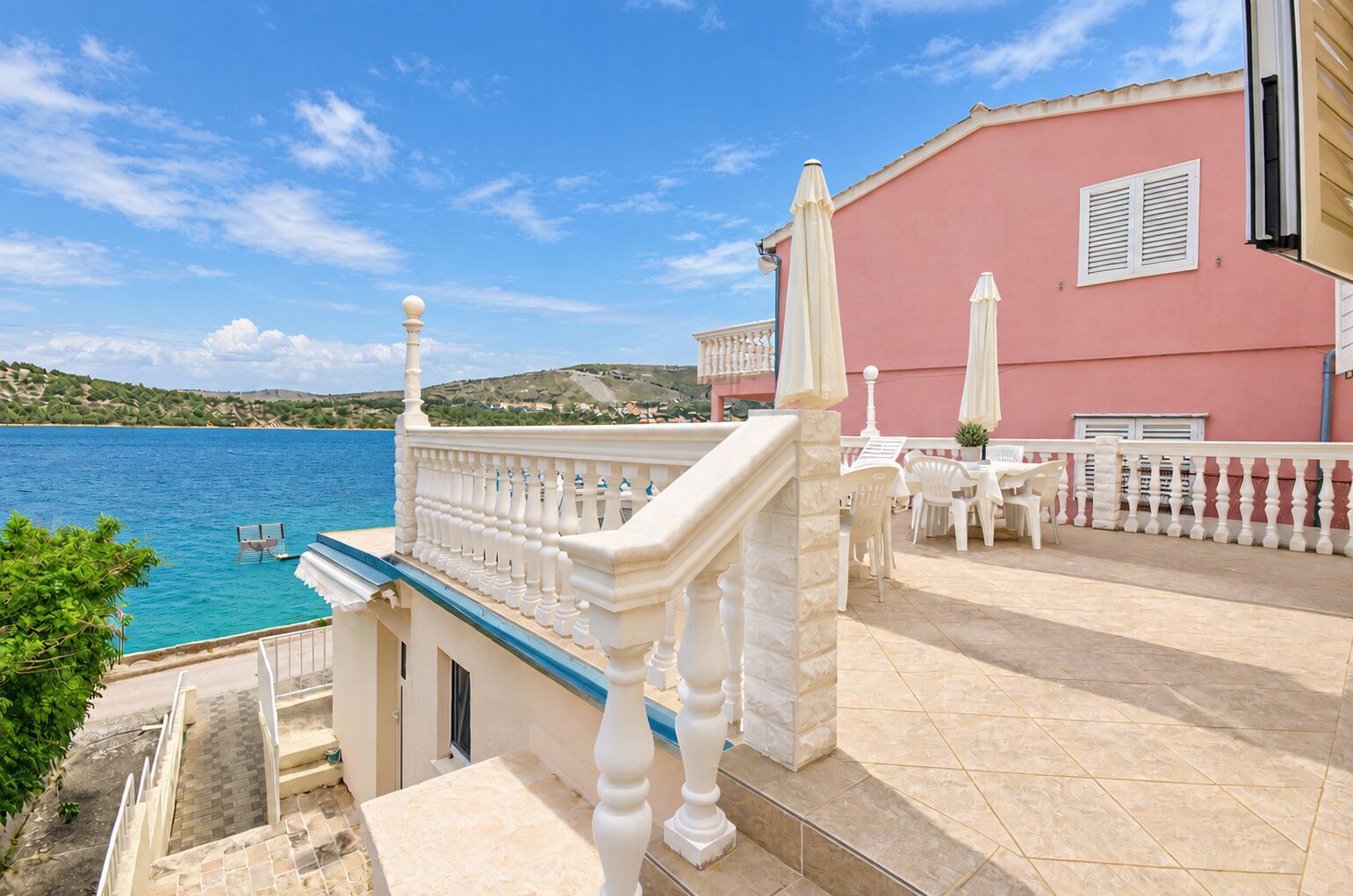 Ein Küstenanwesen mit Balkon, Sitzgelegenheit im Freien und Meerblick.