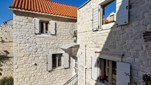 A stone building with a red-tiled roof and white shutters. - House Marijeta and Tonka (Trogir)