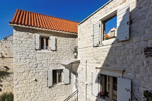 A stone building with a red-tiled roof and white shutters. - House Marijeta and Tonka (Trogir)