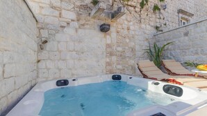 A hot tub adjacent to a stone wall with a lounge area, including a table and chairs. - House Marijeta and Tonka (Trogir)