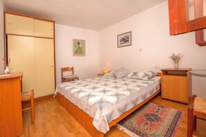 A bedroom with a bed, wooden wardrobe, bedside table, chair, and a rug. - Apartments Marinero (Pakostane)