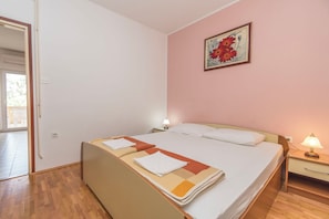 Una habitación de hotel con una cama, una mesita de noche, una lámpara, un cuadro en la pared y una puerta que da a un espacio exterior.