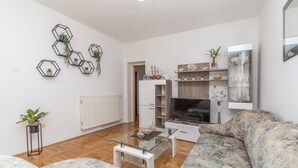 A modern living room with a sofa, a glass coffee table, a TV, and decorative hexagonal wall art. - Apartments Murter Jurjako (Murter-Kornati)