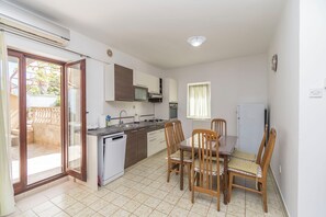 A compact kitchen with a dining area, a built-in microwave, and a small refrigerator. - Apartments Murter Jurjako (Murter-Kornati)