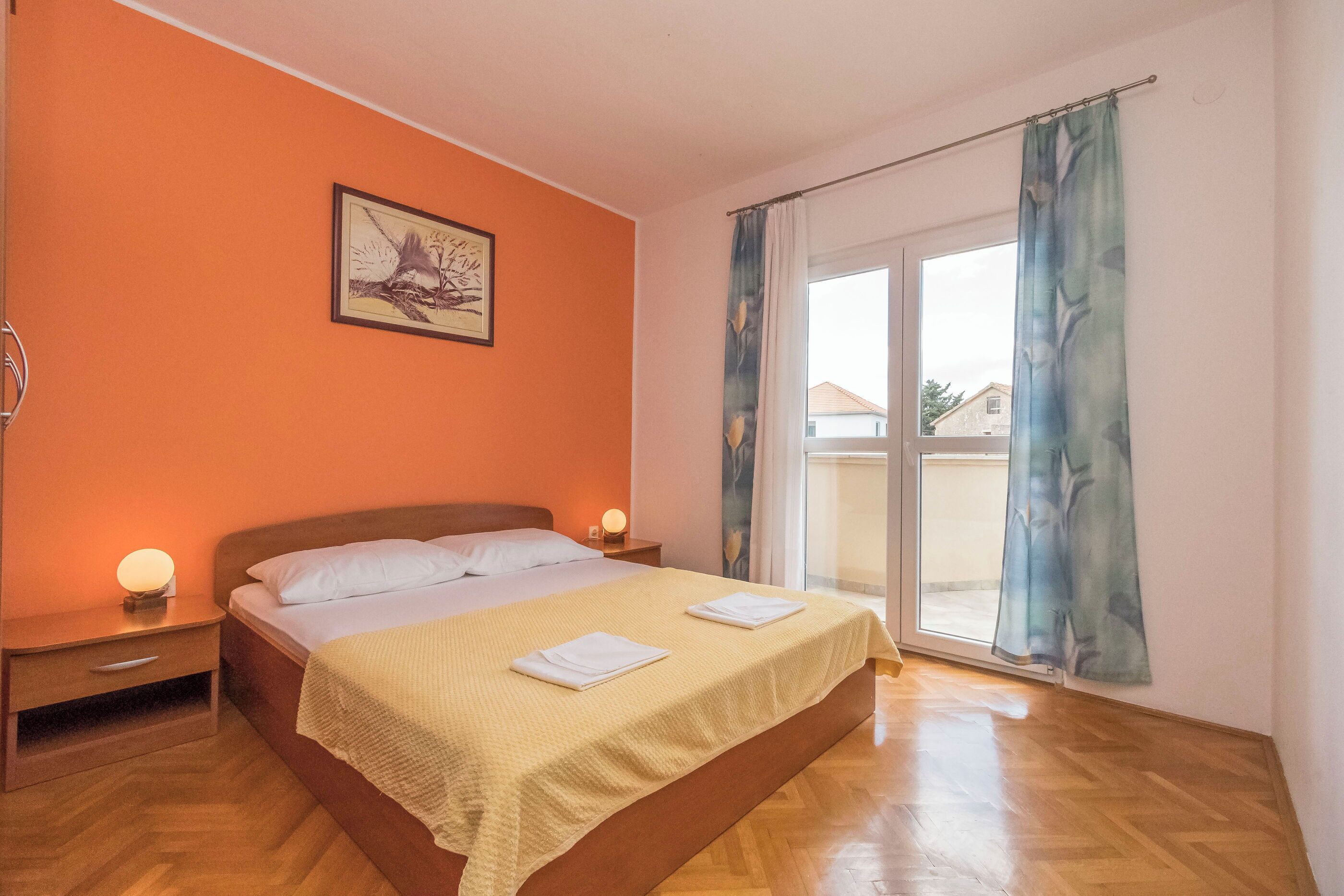 A bedroom with a bed, nightstands, a painting, and a large window with curtains.