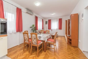 Un comedor con una mesa y sillas de madera, una zona de cocina con estufa y un armario.