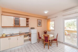 Una cocina compacta con comedor, que incluye refrigerador, estufa, fregadero y una mesa con sillas.
