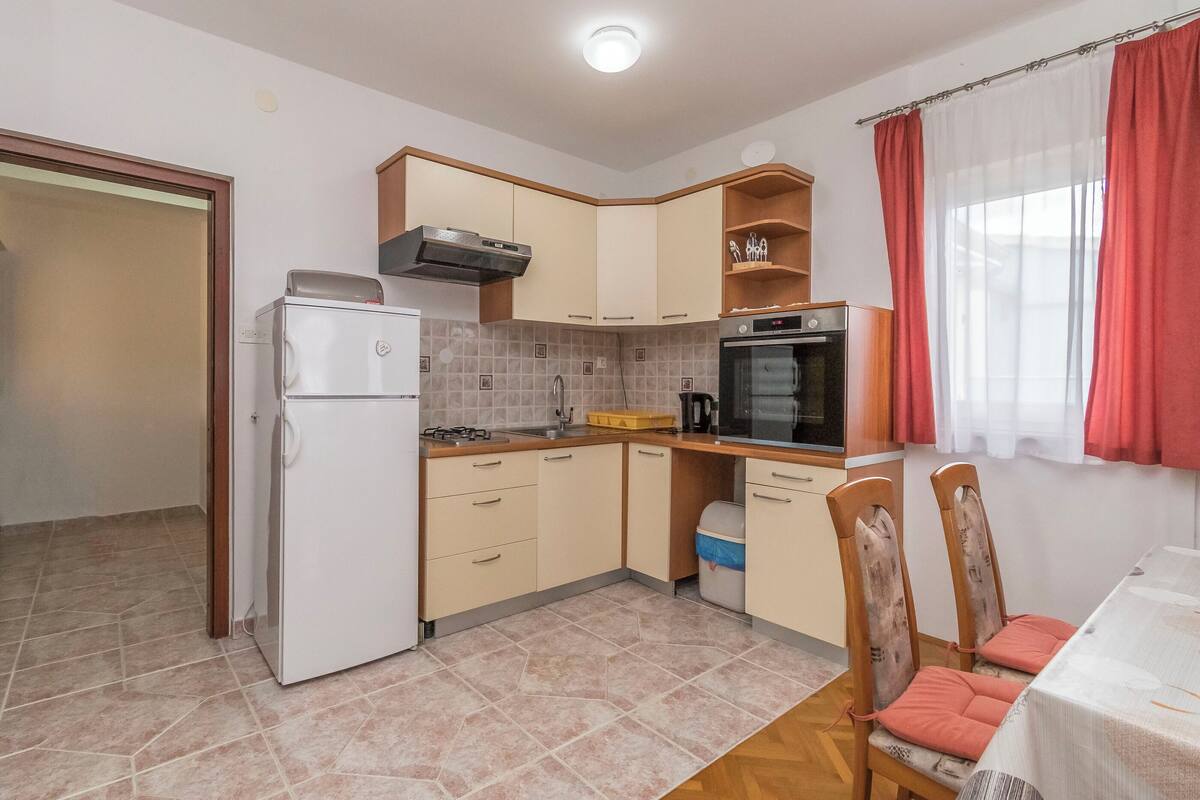 A compact kitchen with a refrigerator, stove, oven, and wooden cabinets.