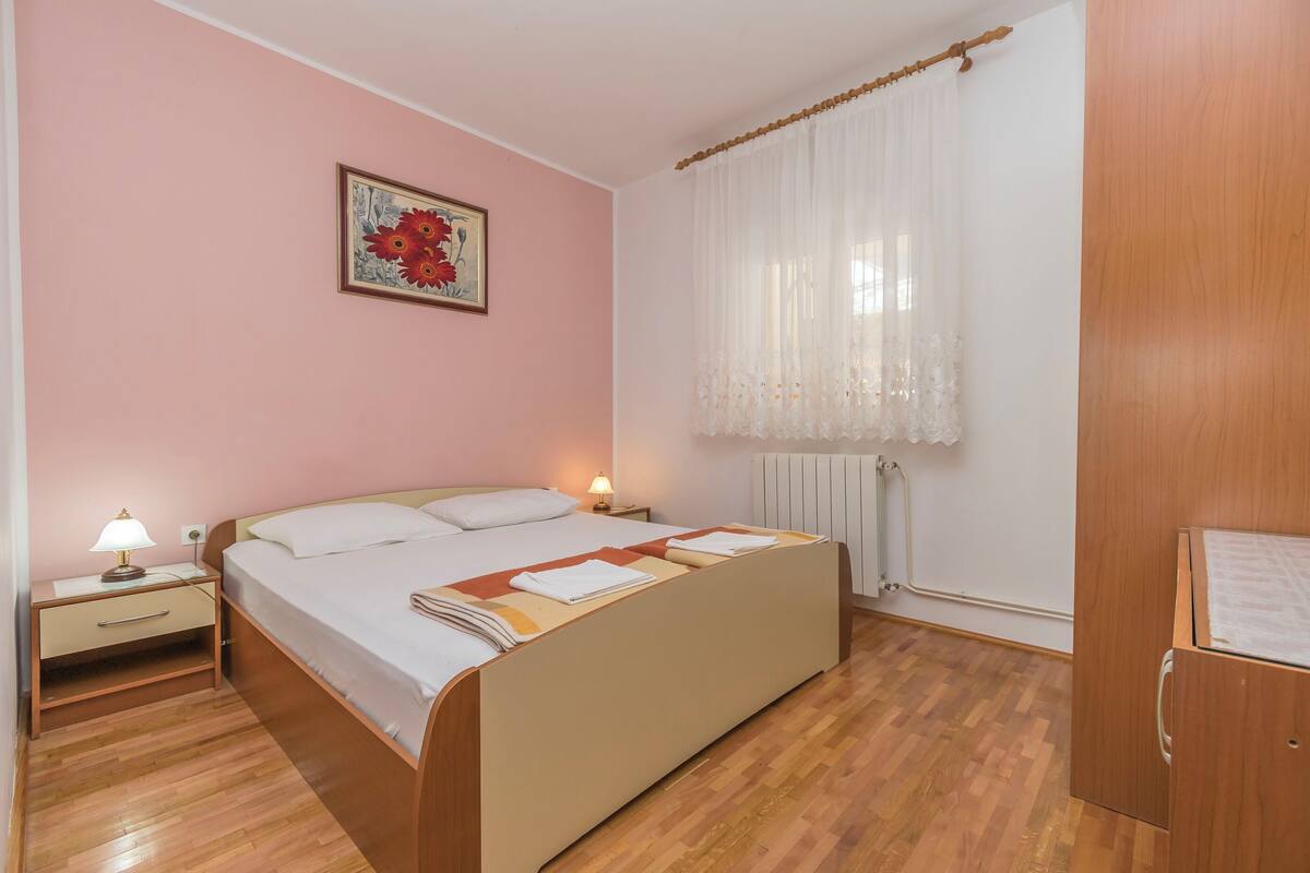 A bedroom with a bed, nightstands, a lamp, a radiator, and a wooden wardrobe.