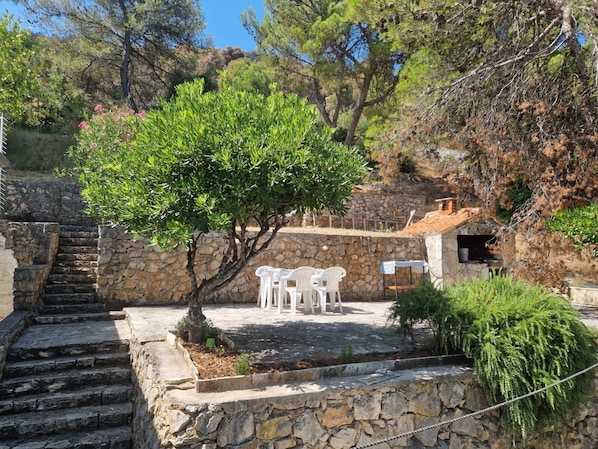 A stone staircase leading to a patio with white chairs and a small table. - Apartment Cosy Terrace (Sibenik)