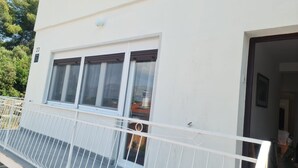 A white building with a balcony, a door, and a window with a curtain. - Apartment Cosy Terrace (Sibenik)