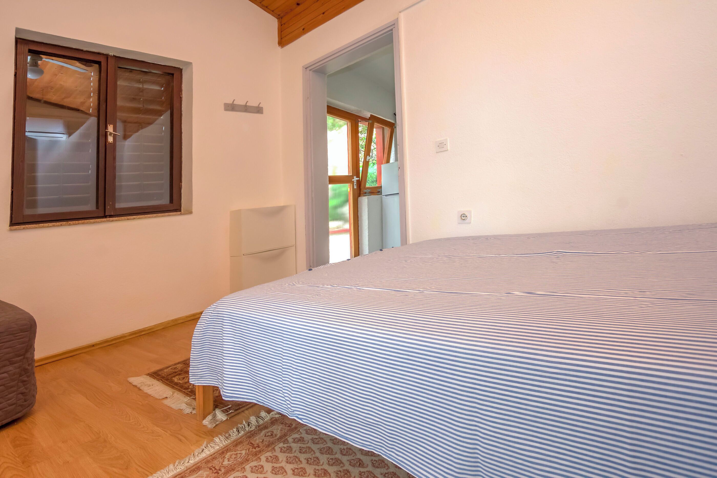 Une chambre avec un grand lit, une porte en bois, une petite table et un tapis à motifs.