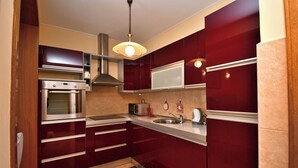 Een compacte keuken met inbouwapparatuur, een oven van roestvrij staal, een magnetron en een spoelbak.