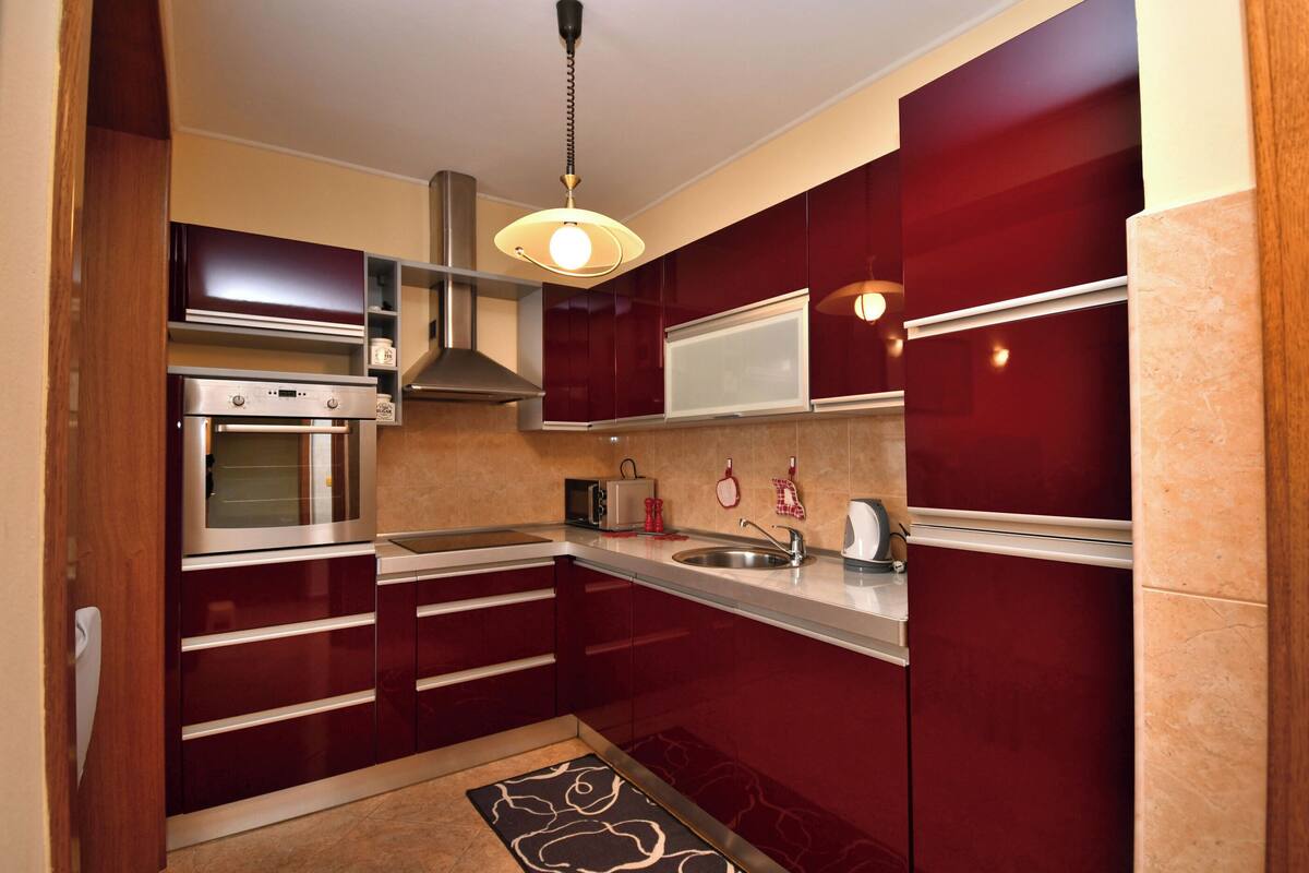 A compact kitchen with built-in appliances, a stainless steel oven, a microwave, and a sink.