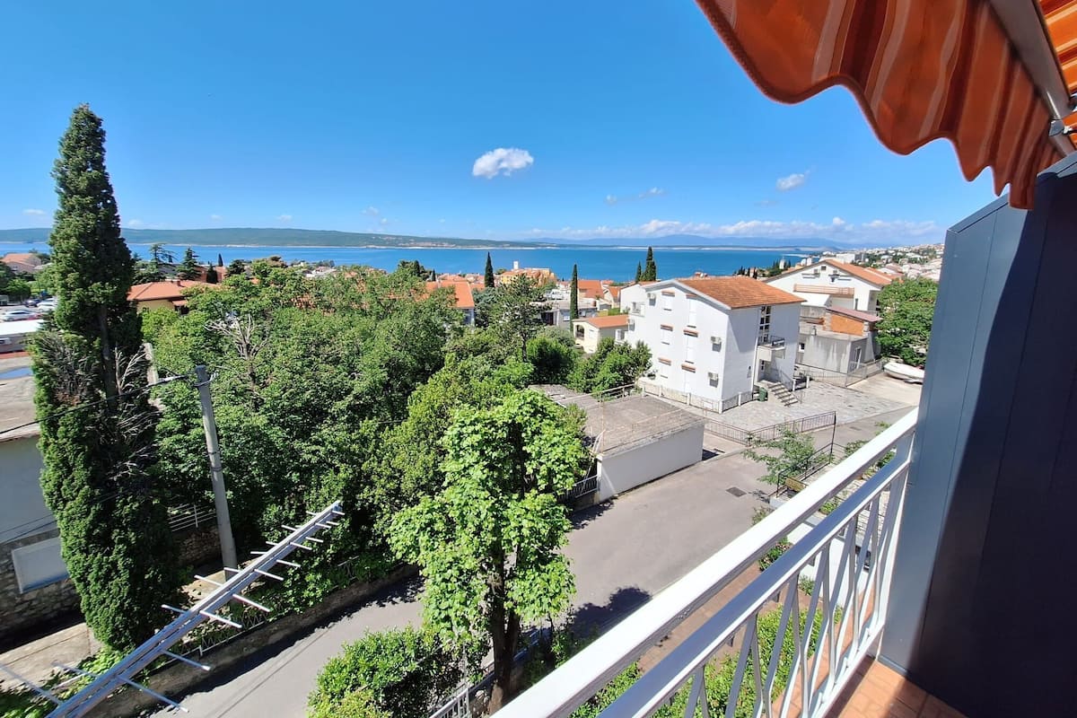 Un balcón con vistas a un pueblo costero, con edificios y árboles.
