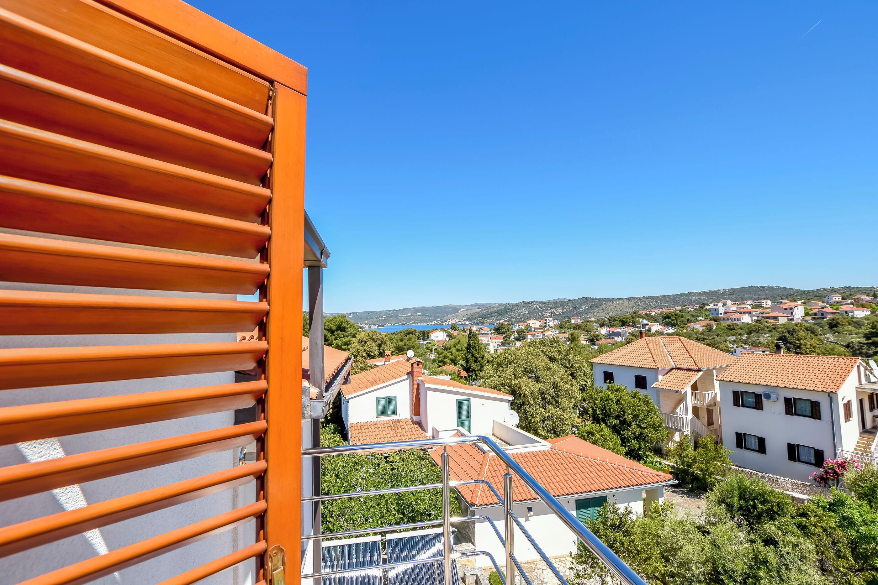 Zona residencial com casas, céu azul límpido e vista para o mar.