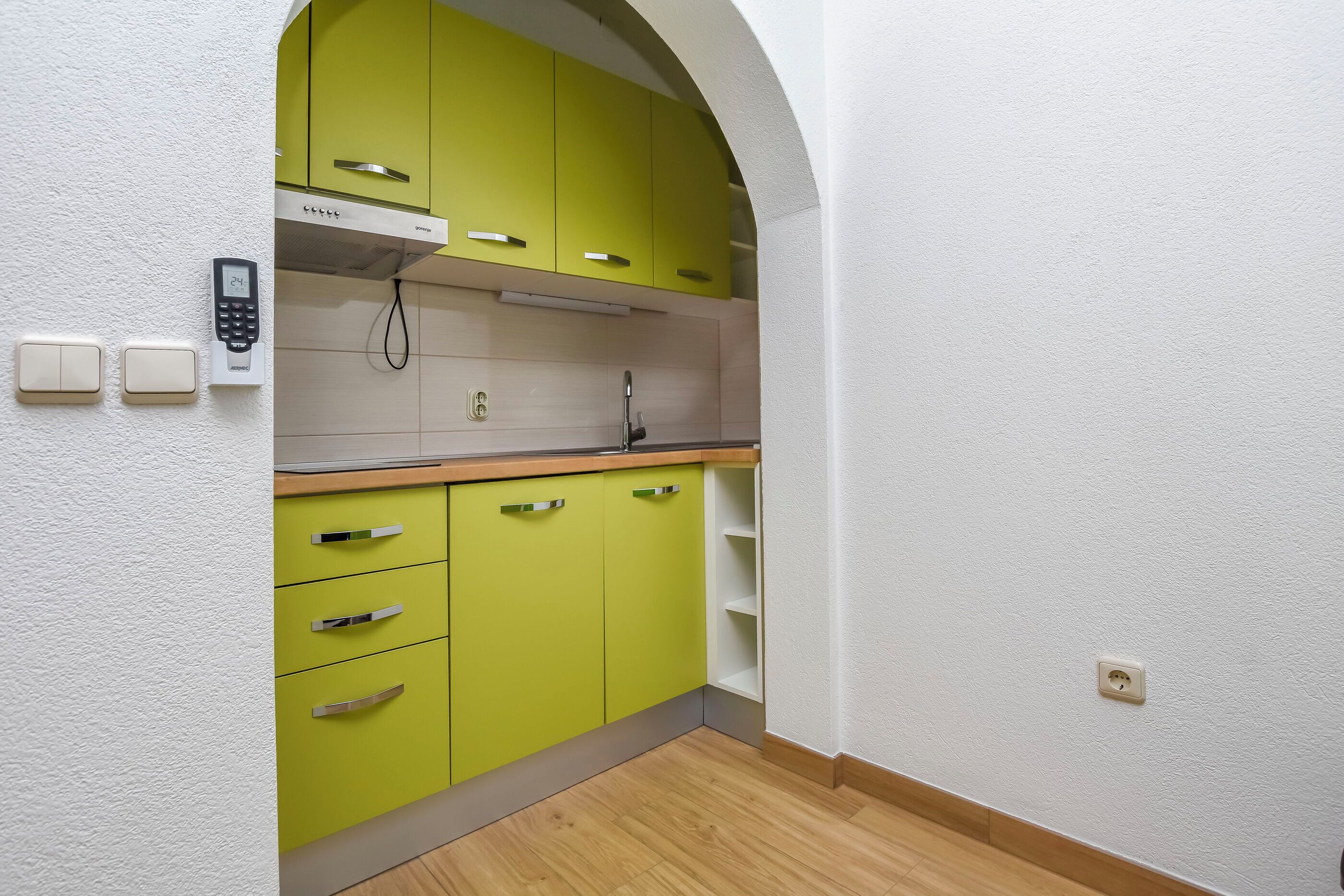 Eine Küche mit grünen Schränken, einem eingebauten Ofen und einem an der Wand befestigten Telefon.