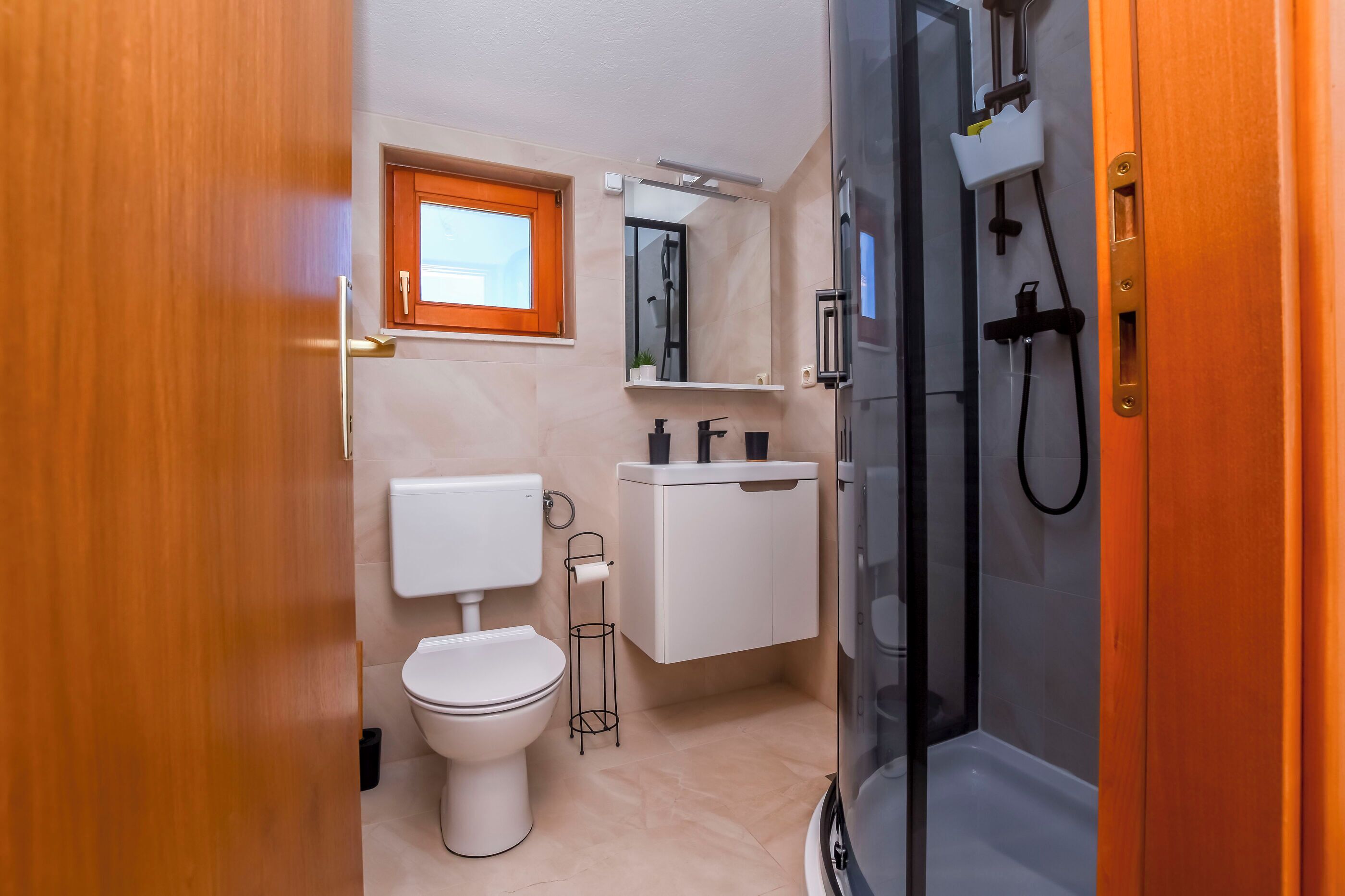 A modern bathroom with a toilet, sink, and shower.