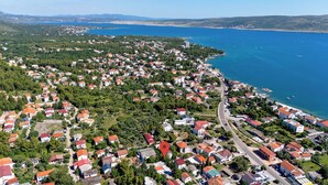 Vue aérienne d’une ville côtière, avec des immeubles résidentiels, une route principale et un port de plaisance où sont amarrés des bateaux.