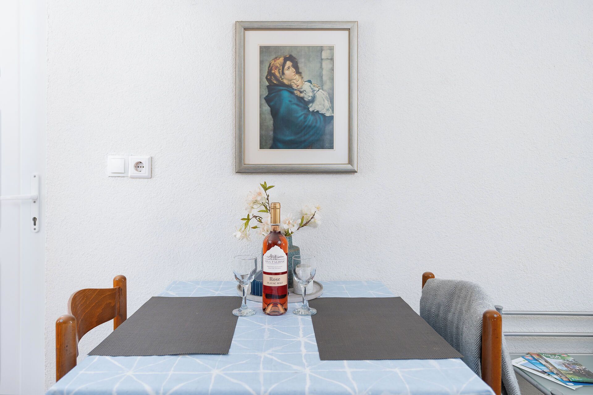 A dining table with a bottle of wine, a glass, and a vase with flowers.