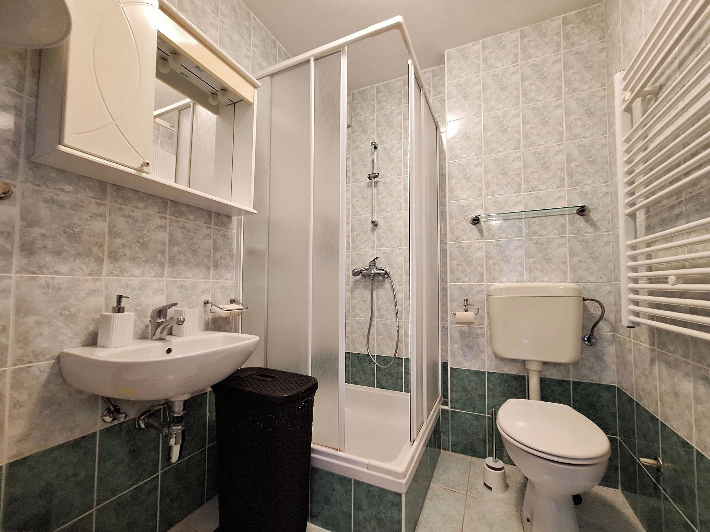Un baño moderno con ducha, inodoro, lavabo y mampara de vidrio.