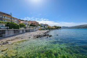 Une vue dégagée sur le front de mer, avec des bâtiments, une côte rocheuse et une mer calme.