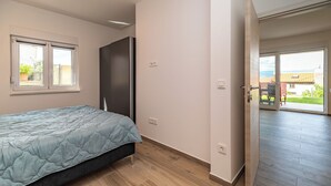 A bedroom with a bed, a wardrobe, a door leading to a balcony, and a window. - Apartment Krtica (Vrbnik)
