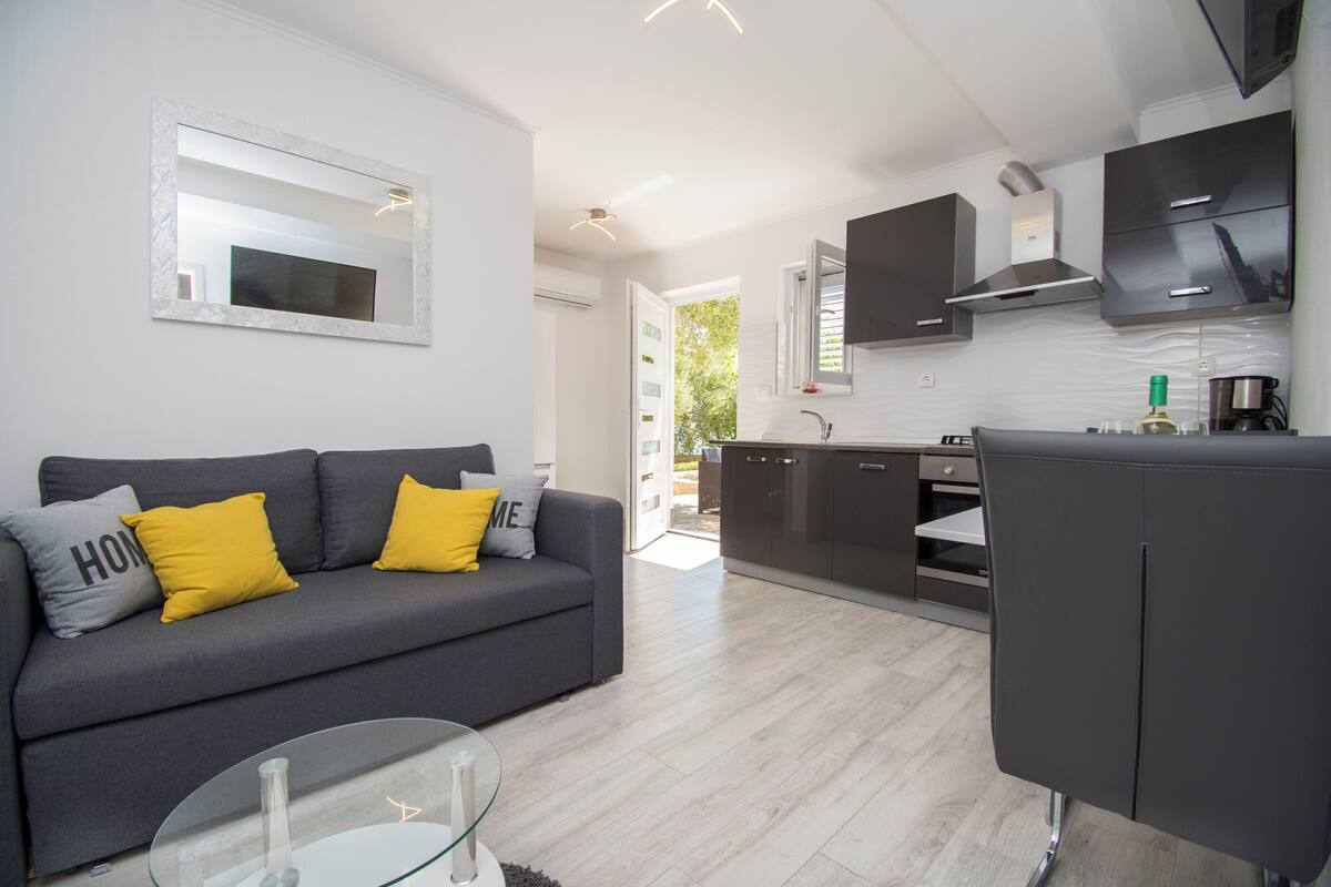A modern living room with a grey sofa, yellow cushions, and a glass coffee table.