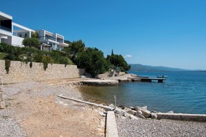 A coastal property with a stone wall, a wooden dock, and a clear view of the sea. - Apartment Ana (Jasenice)