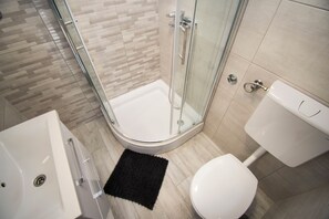 A modern bathroom with a glass-enclosed shower, a white toilet, and a bathtub. - Apartment Ana (Jasenice)