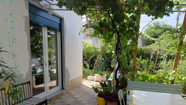 A patio with a bench, a table, and potted plants. - Apartment Nina (Rab)