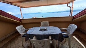 Un petit balcon avec une table et des chaises, donnant sur une étendue d’eau et sur des montagnes lointaines.