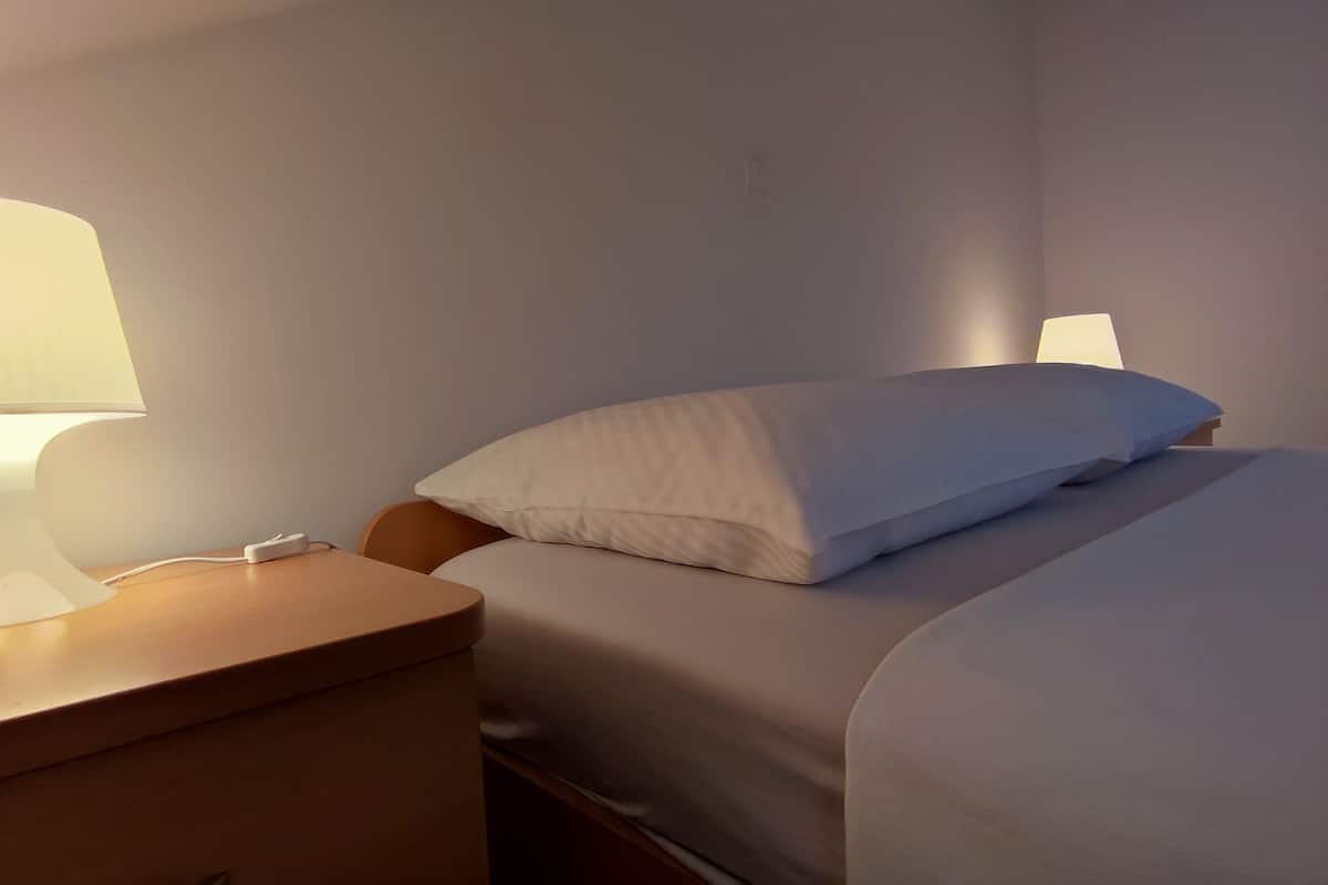 A hotel room with a bed, a nightstand, and a bedside lamp.