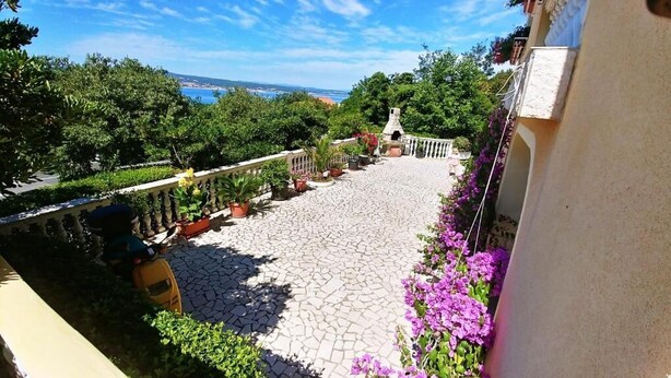 Une cour avec un sol en pierre, des plantes en pot et une vue sur la mer.
