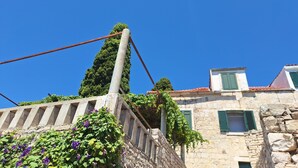 Un edificio de piedra con contraventanas verdes y un cielo azul despejado.