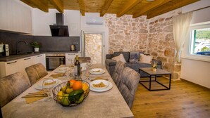 A cozy dining area with a stone wall, a stone fireplace, and a view of the outdoors. - House Olivera (Tribunj)