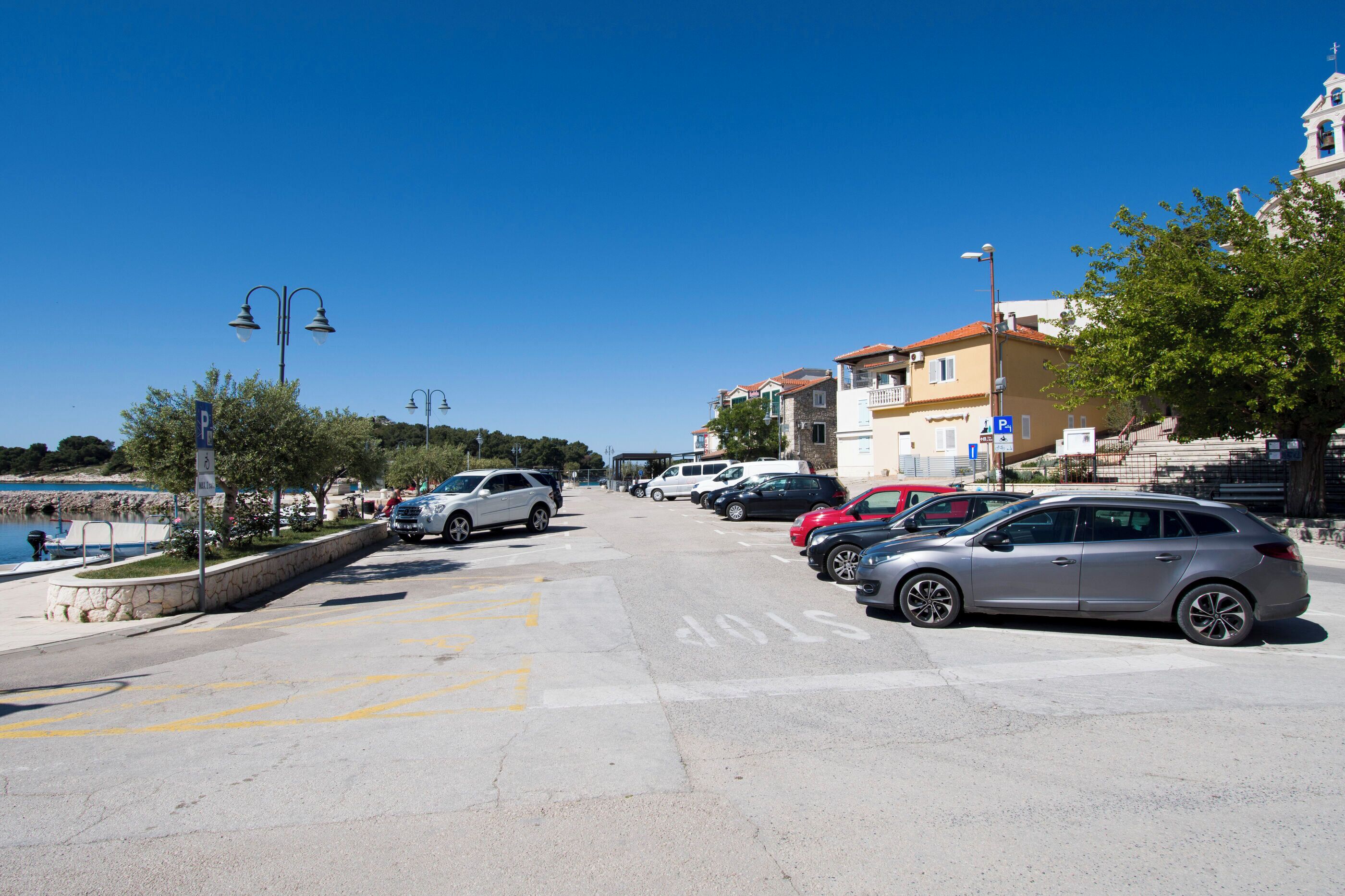 Ein Parkplatz mit Autos, ein Gebäude mit Balkonen und einem strahlend blauen Himmel.