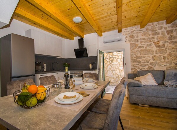 Una cocina moderna con pared de piedra, techo de madera y un comedor con una mesa preparada para dos.