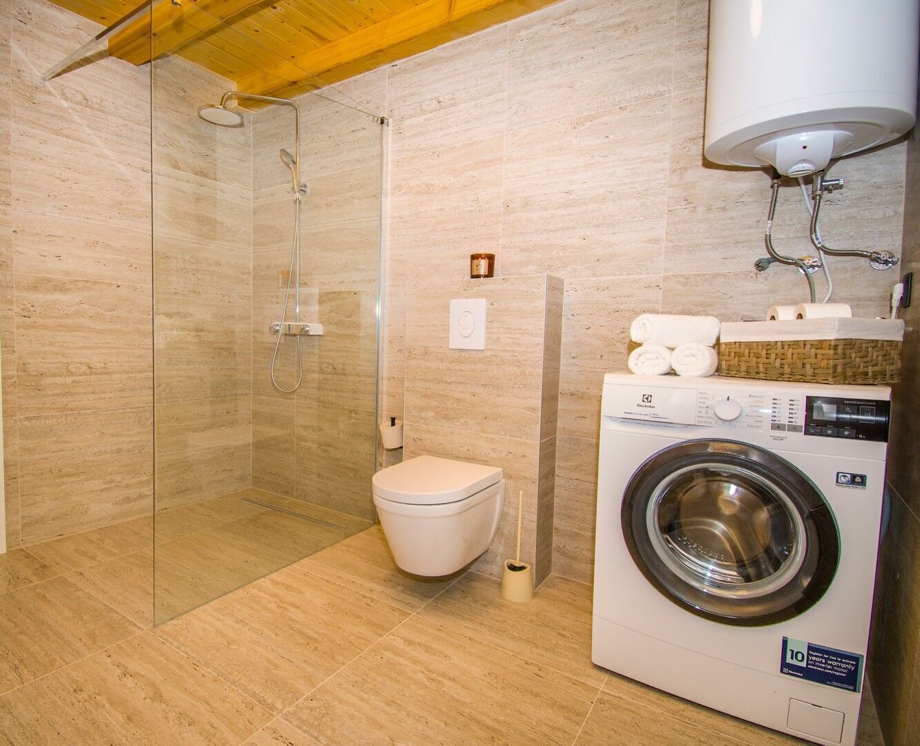 Une salle de bain avec une douche à parois de verre, des toilettes et un lave-linge à chargement frontal.