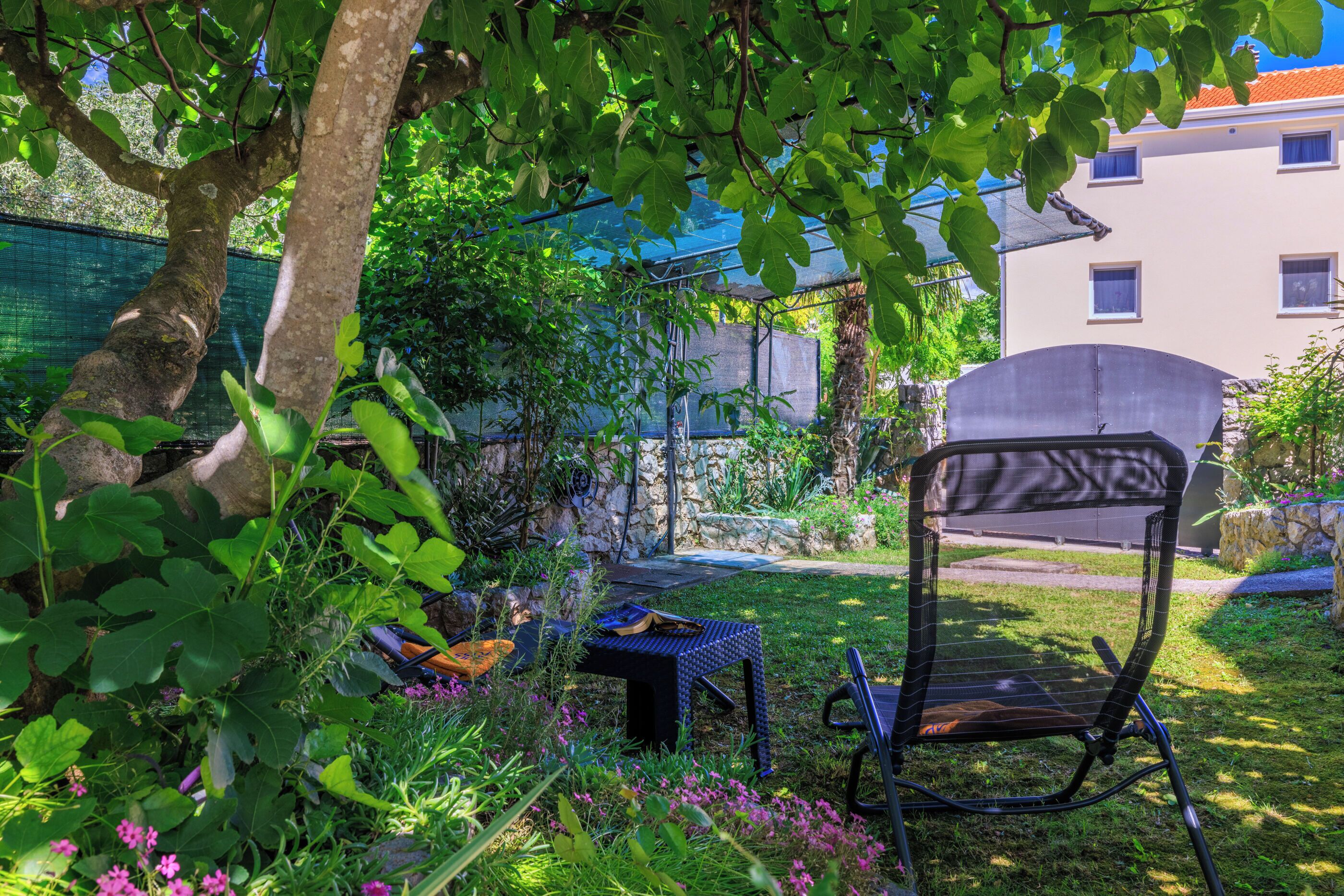 A garden area with a chair, a table, and a tree.