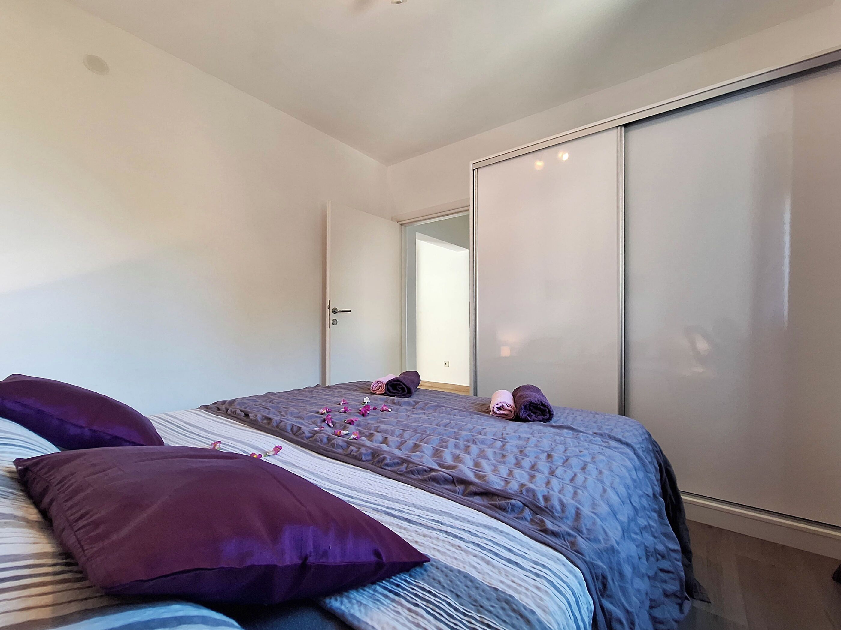 Een slaapkamer met een bed, kussens en een kledingkast.