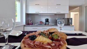 Een verzorgd charcuteriebord met diverse vleessoorten, kazen en fruit, gepresenteerd op een houten plank, staand op een tafel met wijnglazen en bestek.