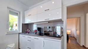 Een moderne keuken met witte kastjes, een roestvrijstalen afzuigkap en een ingebouwde vaatwasser.
