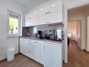 Una cocina moderna con armarios blancos, una campana de acero inoxidable y un lavavajillas integrado.