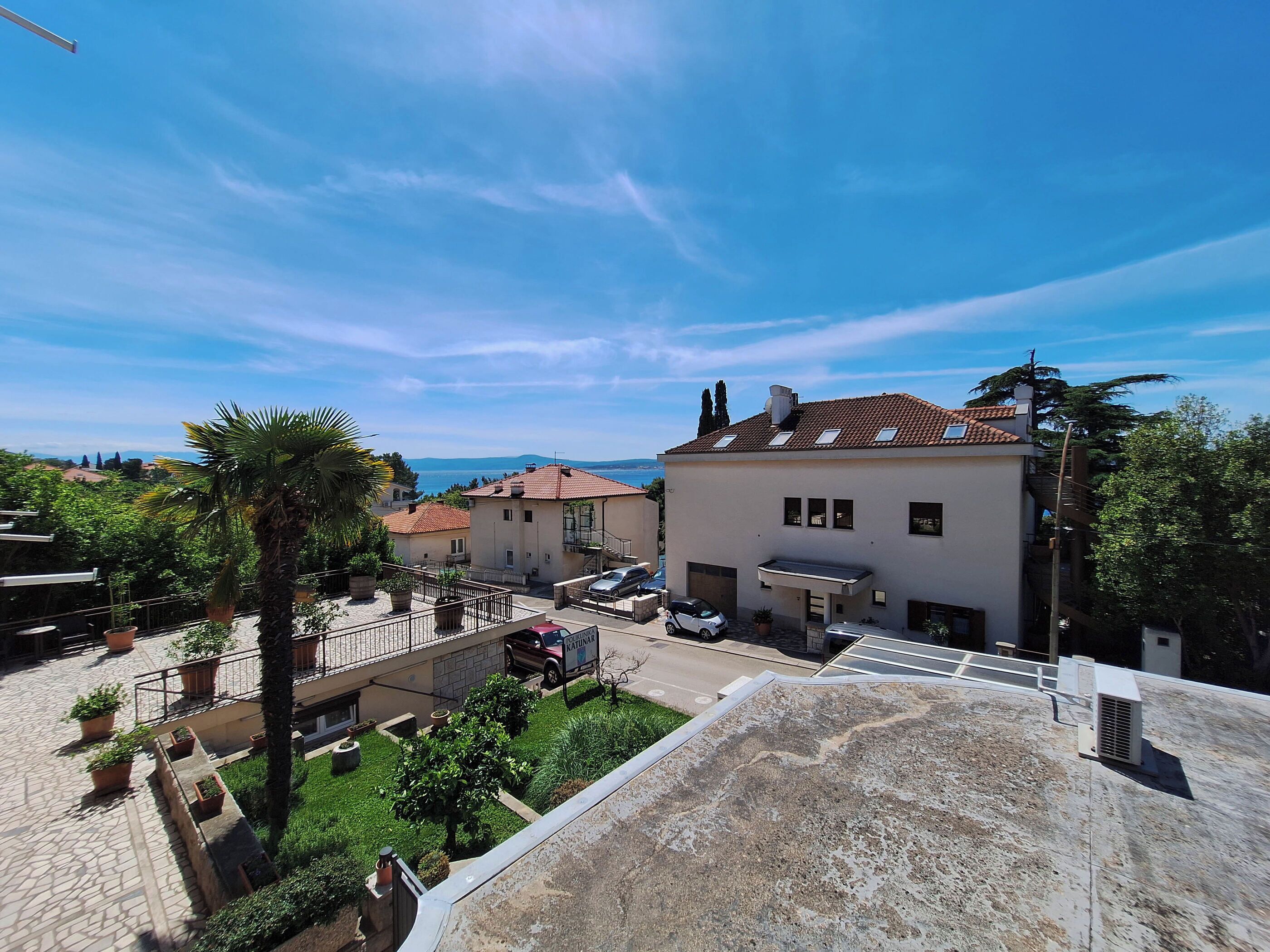 Zona residencial con una casa que tiene un panel solar, un automóvil y un pequeño jardín.