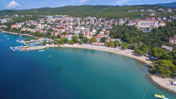 An aerial view of a coastal town with a marina, beach, and residential buildings. - Apartment and Rooms Katunar (Crikvenica)