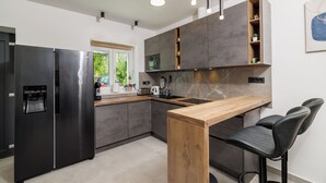 Una cocina moderna con un refrigerador empotrado, una barra de madera y taburetes negros.